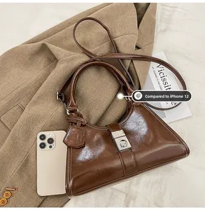 Detail showing the brown glossy leather texture and silver buckle next to a phone