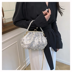 Detail of elegant white shell bag with pearl handle and grey butterfly patterns