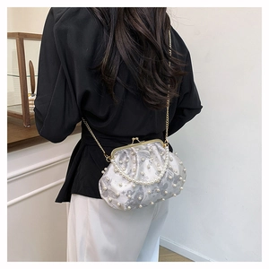 Detail of white pearl clutch with butterfly print and vintage gold metal clasp chain