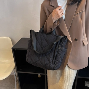 Quilted black tote bag with adjustable shoulder strap and padded finish in urban setting
