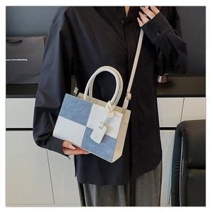 Dettaglio della borsa in denim blu e pelle bianca con manici e tracolla regolabile