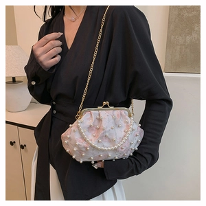 Detail of elegant pearl-embellished seashell bag with gold chain strap on model