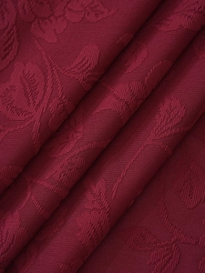 Macro detail of burgundy damascus jacquard fabric with elegant floral relief patterns
