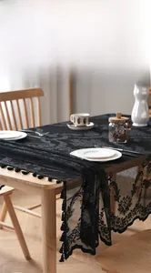 Detail of black lace tablecloth featuring intricate hollow floral patterns and fringe tassels
