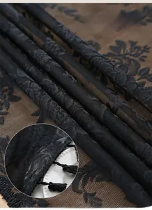 Detailed macro view of black lace fabric with rose patterns and delicate tassel edges