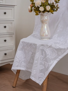 Detail of white lace tablecloth with vintage rose floral embroidery and scalloped edges