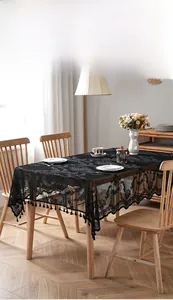 Macro detail of black lace tablecloth with floral hollow patterns and tassel fringe
