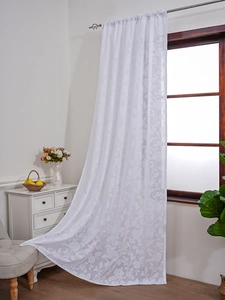 Detail of white lace curtain with delicate floral embroidery and sheer texture