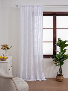 Detail of white lace sheer curtain featuring intricate floral embroidery and leaf patterns
