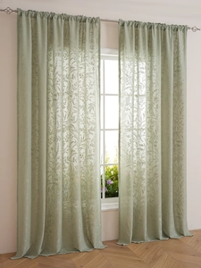 Detail view of light green lace curtains with floral patterns and semi-sheer texture