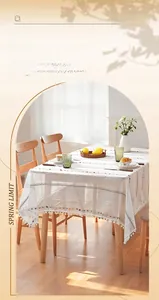 Close-up of white sheer tablecloth with colorful polka dot embroidery and pom-poms