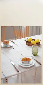 Close-up of retro minimalist tablecloth with vertical stripes and colorful pompom details