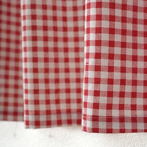 Detailed close-up of red and white gingham cotton linen cafe curtain with stitched edges
