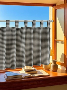 Close-up of black and white plaid cafe curtain hanging on a rustic wooden window frame