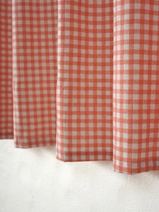 Close-up of orange and white checkered thick linen cotton kitchen curtain with rich texture