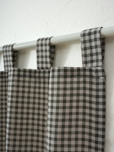 Detail of black and white gingham tab top cafe curtain on a white rod for kitchen