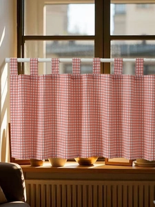 Detail of red and white checkered cafe curtain with tab top hanging on a wooden window