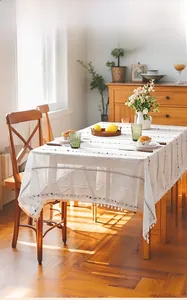 Nordic white tablecloth with colorful embroidery and pom-pom fringe on a wooden table