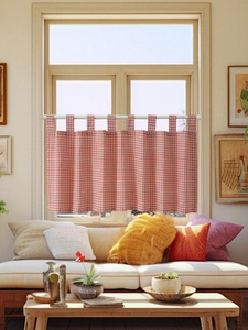 Detail of red and white gingham cafe curtain with tab top design hanging on a white rod
