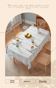 Detail of cream cotton linen tablecloth with colorful stripes and white pom-pom fringe