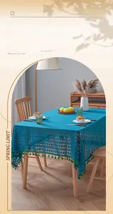 Detailed texture of peacock blue lace tablecloth with hollow stripes and green tassels