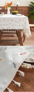 Close-up of candy embroidery and fringe tassels on a thick cream cotton linen tablecloth