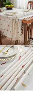 Detail of colorful candy embroidery and beige linen fabric with tassel edge on tablecloth