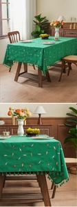 Close-up of green tablecloth featuring colorful candy embroidery and tassel fringe details