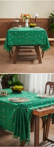 Close-up of emerald green tablecloth featuring colorful candy embroidery and tassel fringe