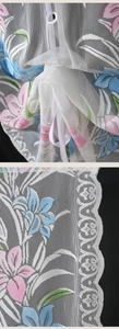 Detail of floral printed mesh fabric with delicate white lace border on a lift curtain