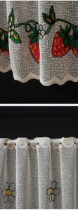 Close-up of white lace curtain with red strawberry and daisy flower embroidery detail