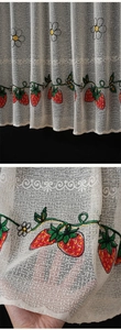 Close-up of strawberry and daisy embroidery on white translucent lace cafe curtains