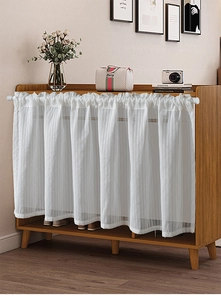 Close-up of white pleated cafe curtain with vertical stripes on a wooden cabinet