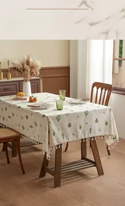 Detail of linen tablecloth with green cactus patterns and white tassel fringe