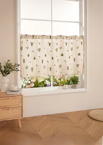Detail of linen cafe curtain with cactus embroidery and white pom-pom tassel trim