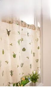 Detail of embroidered green cactus patterns and delicate tassels on linen half curtain