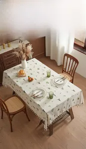 Detail showing beige linen tablecloth with green cactus prints and tassel fringe edges