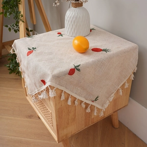 Tovaglia in lino con ricamo a carota e nappe bianche su un comodino in legno massello