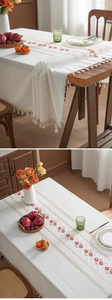 Detail of cream tassel tablecloth with red-brown diamond embroidery on thick woven fabric