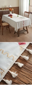 Close-up of geometric red and gold embroidery on cream cotton linen tablecloth with tassels