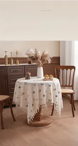 Close-up of thick linen tablecloth with yellow floral embroidery and fringe edge
