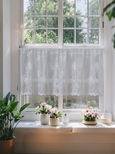 Détail d'un rideau de café en dentelle blanche avec broderie palmier et bords festonnés