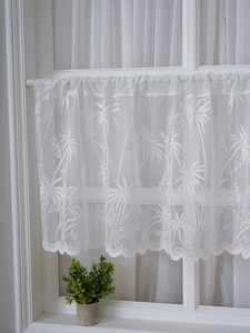 Detail of white lace cafe curtain featuring palm tree embroidery and scalloped edges