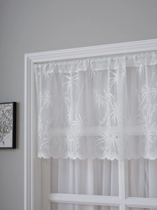 Detailed view of white lace cafe curtain featuring palm tree patterns and scalloped edges