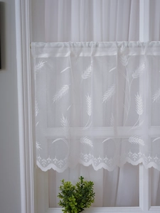 Détail macro de rideau de café en dentelle blanche avec broderie de blé et festons