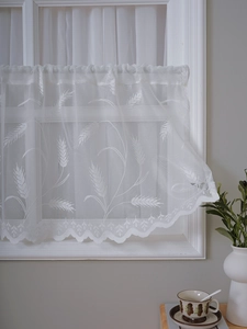 Detail of white lace cafe curtain with wheat embroidery and scalloped wavy edges