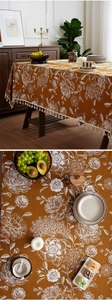 Close-up of caramel tablecloth with white floral patterns and elegant cotton tassels