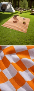 Detail of orange checkered picnic mat showing durable woven fabric texture on grass
