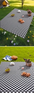 Close-up of black and white checkered picnic mat spread on lush green grass in a park