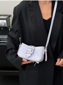 Detail of lavender stone-patterned crossbody bag with oversized square buckle on black blazer